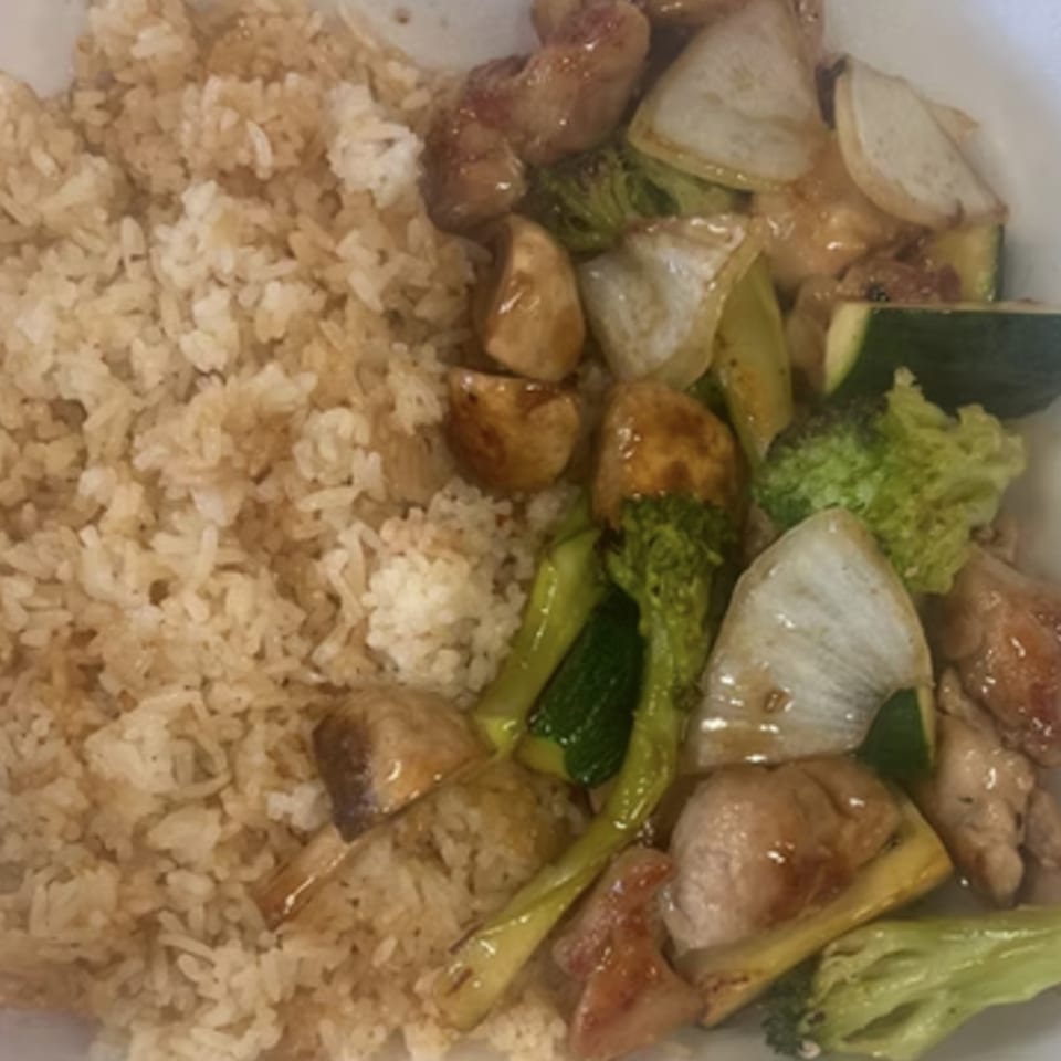 Chicken stir-fry with broccoli, zucchini, onions, and mushrooms, served with brown rice.
